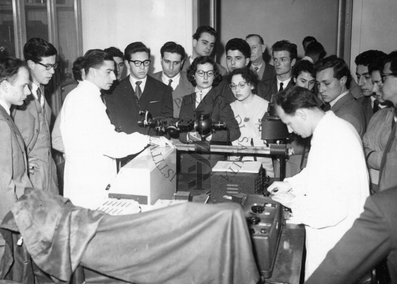 Il gruppo degli studenti di medicina dell'Università di Firenze in visita presso l'Istituto Superiore di Sanità osservano il lavoro di due dipendenti dell'Istituto in camice bianco all'interno di uno dei laboratori. Accompagna il gruppo il Dott. Massimo Pantaleoni dell'Istituto, in fondo alla foto parzialmente coperto.