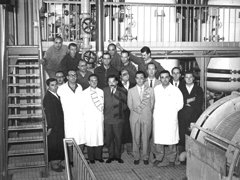 Foto di gruppo con al centro il Prof. Ernst Boris Chain, all'interno dell'edificio che ospitava i fermentatori per la fabbricazione della penicillina