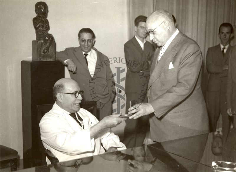 Il Prof. Domenico Marotta (in piedi a destra) consegna la medaglia d'oro per i 50 anni di onorato servizio al Prof. Giulio Cesare Trabacchi (seduto con il camice)