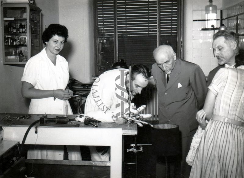 S. E. Giovanni Battista Bertone (terzo da sinistra) in un laboratorio dell'Istituto Superiore di Sanità in compagnia del prof. Daniel Bovet (secondo da sinistra), della prof.ssa Maria Marotta e del senatore Giuseppe Alberti