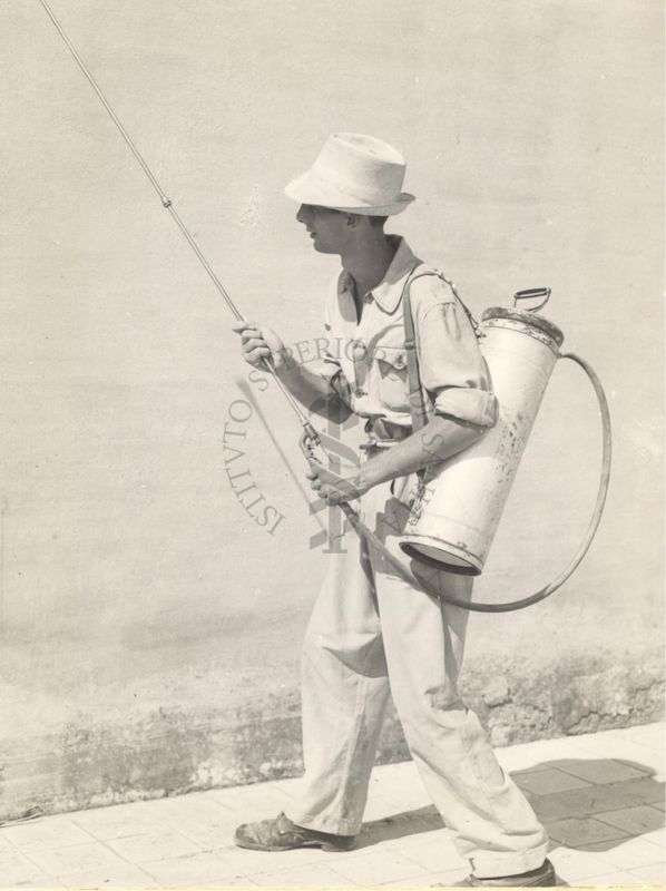 Individuo mostra un tipo di pompa a mano per disinfezioni antimalariche