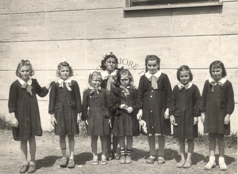 Gruppo di bambine con grembiule scuro e colletto bianco