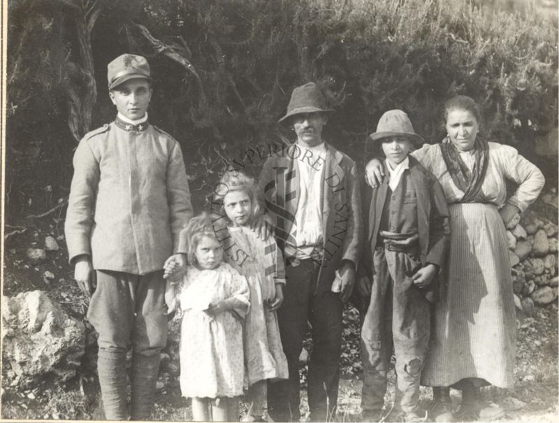 Foto di una famiglia affetta da malaria con ragazzo in divisa militare sulla sinistra.
