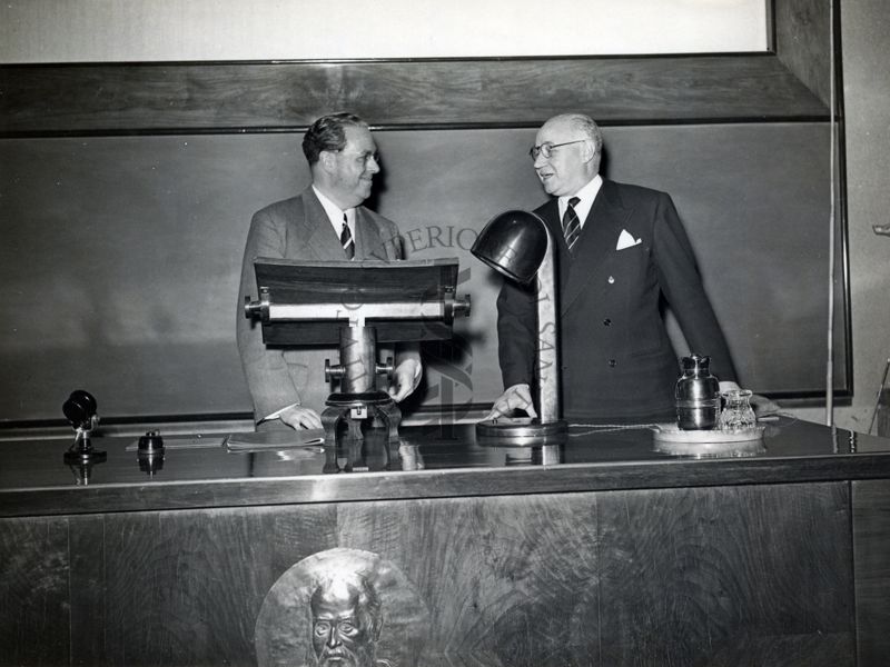 Il Prof. Louis Justin-Besancon (a sinistra) e il Prof. Marotta (a destra) ripresi dietro il tavolo dei relatori in occasione della conferenza tenuta dal Prof. Justin-Besancon all'Istituto Superiore di Sanità