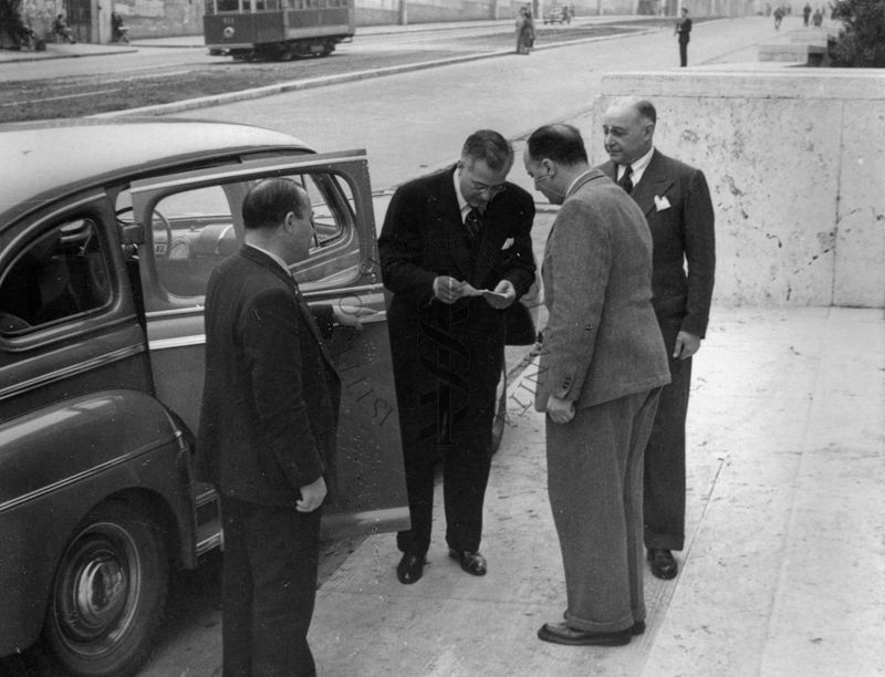 Quattro persone che salutano l'Avv. Marchisi (secondo da sinistra) prima di entrare in macchina. Possiamo notare il prof. D. Marotta (primo da destra).