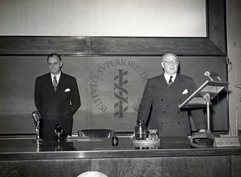 Il Prof. Domenico Marotta (a destra) dietro al tavolo dei relatori presenta il Prof. H. Corwin Hinshaw (a sinistra) invitato a tenere una conferenza all'Istituto Superiore di Sanità