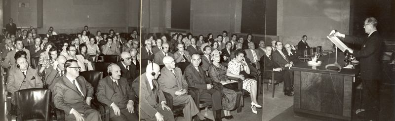 Ripresa del Prof. Weiss, in piedi alla cattedra, e l'uditorio presente alla sua conferenza in aula magna. Sono inquadrati, in prima fila, da destra: Prof Marotta (primo), Prof. Bovet (terzo), Dott.ssa Beloff-Chain (quarta). Sempre in prima fila è presente il Prof. Penso (primo da sinistra).