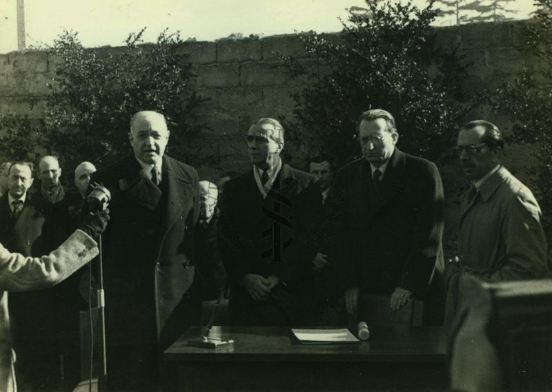 Cerimonia della posa della prima pietra per l'erigendo Istituto della Penicillina. Parla il prof. Domenico Marotta, alla sua sinistra l'Ambasciatore d'America James Clement Dunn, segue il Presidente del Consiglio Alcide de Gasperi, infine l'Alto Commissario per l'Igiene e la Sanità Pubblica Nicola Perotti (con soprabito chiaro)