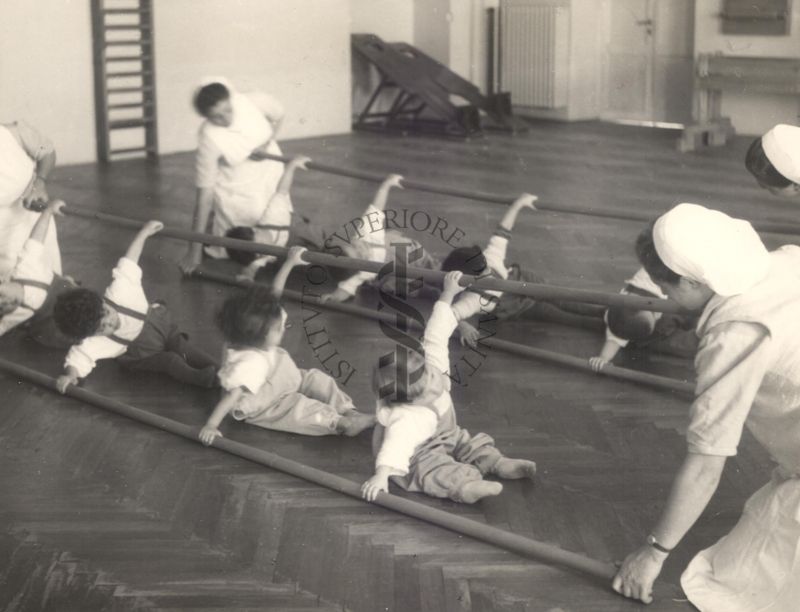 Sala per la ginnastica collettiva dell'Istituto Ortopedico "Luigi Spolverini" di Ariccia (Roma) - delle infermiere sorreggono alcune aste per guidare i movimenti dei bambini