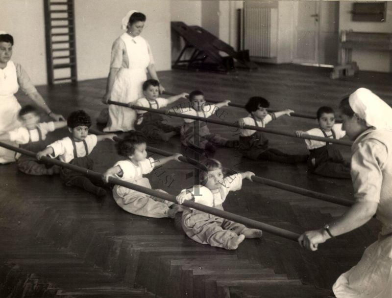 Sala per la ginnastica collettiva dell'Istituto Ortopedico "Luigi Spolverini" di Ariccia (Roma) - delle infermiere sorreggono alcune aste per guidare i movimenti dei bambini