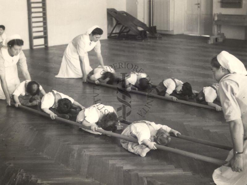 Sala per la ginnastica collettiva dell'Istituto Ortopedico "Luigi Spolverini" di Ariccia (Roma) - delle infermiere sorreggono alcune aste per guidare i movimenti dei bambini