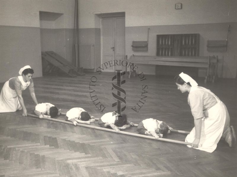 Sala per la ginnastica collettiva dell'Istituto Ortopedico "Luigi Spolverini" di Ariccia (Roma) - delle infermiere sorreggono alcune aste per guidare i movimenti dei bambini