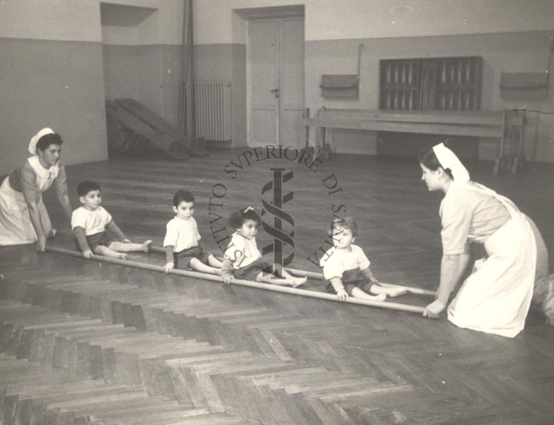 Sala per la ginnastica collettiva dell'Istituto Ortopedico "Luigi Spolverini" di Ariccia (Roma) - delle infermiere sorreggono alcune aste per guidare i movimenti dei bambini