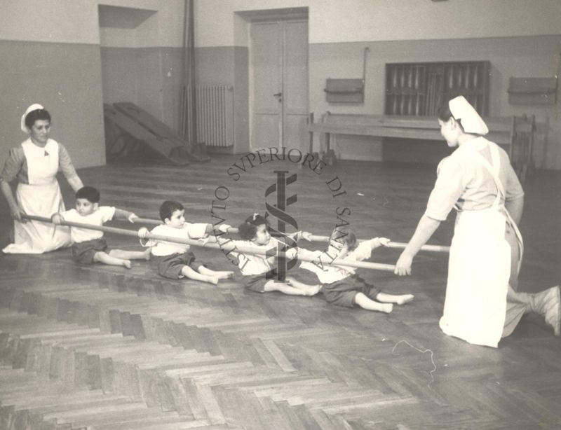 Sala per la ginnastica collettiva dell'Istituto Ortopedico "Luigi Spolverini" di Ariccia (Roma) - delle infermiere sorreggono alcune aste per guidare i movimenti dei bambini