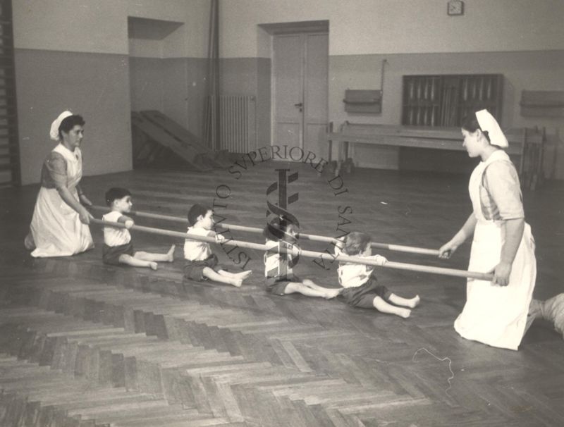 Sala per la ginnastica collettiva dell'Istituto Ortopedico "Luigi Spolverini" di Ariccia (Roma) - delle infermiere sorreggono alcune aste per guidare i movimenti dei bambini