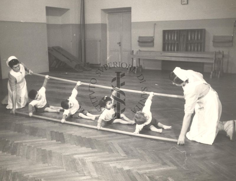 Sala per la ginnastica collettiva dell'Istituto Ortopedico "Luigi Spolverini" di Ariccia (Roma) - delle infermiere sorreggono alcune aste per guidare i movimenti dei bambini