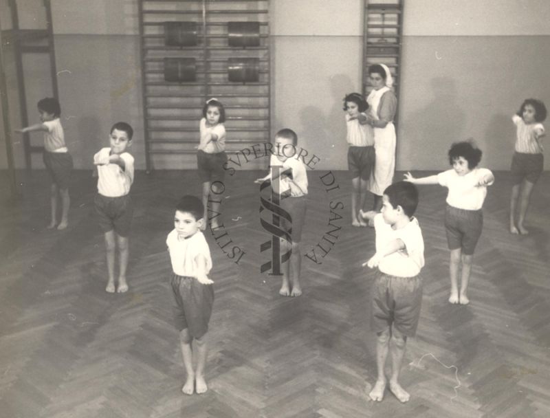 Sala per la ginnastica collettiva dell'Istituto Ortopedico "Luigi Spolverini" di Ariccia (Roma) - un'infermiera controlla la postura di un gruppo di bambini che svolgono esercizi ginnici