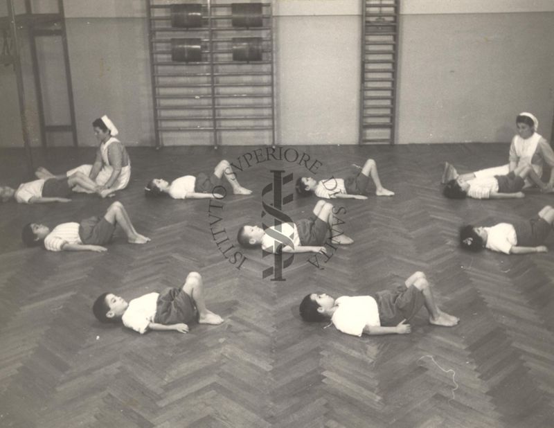 Sala per la ginnastica collettiva dell'Istituto Ortopedico "Luigi Spolverini" di Ariccia (Roma) - delle infermiere controllano la postura di un gruppo di bambini che svolgono esercizi ginnici