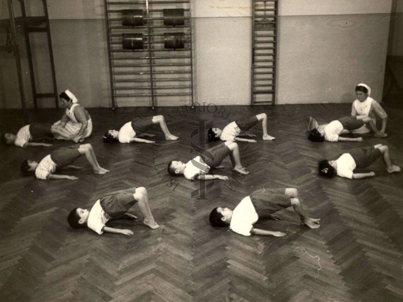 Sala per la ginnastica collettiva dell'Istituto Ortopedico "Luigi Spolverini" di Ariccia (Roma) - delle infermiere controllano la postura di un gruppo di bambini che svolgono esercizi ginnici