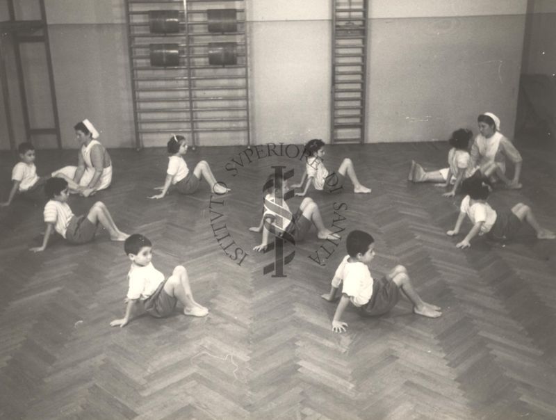 Sala per la ginnastica collettiva dell'Istituto Ortopedico "Luigi Spolverini" di Ariccia (Roma) - delle infermiere controllano la postura di un gruppo di bambini che svolgono esercizi ginnici