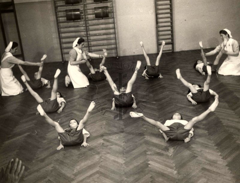 Sala per la ginnastica collettiva dell'Istituto Ortopedico "Luigi Spolverini" di Ariccia (Roma) - delle infermiere controllano la postura di un gruppo di bambini che svolgono esercizi ginnici