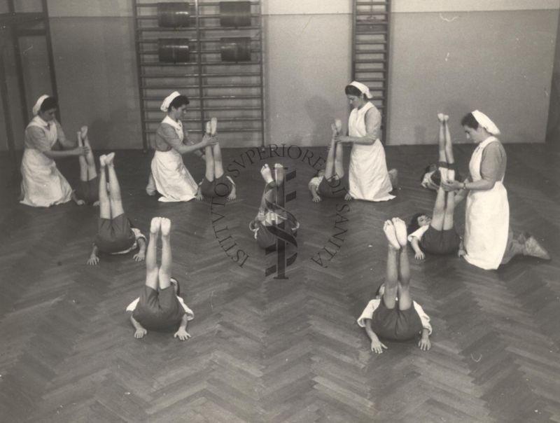 Sala per la ginnastica collettiva dell'Istituto Ortopedico "Luigi Spolverini" di Ariccia (Roma) - delle infermiere controllano la postura di un gruppo di bambini che svolgono esercizi ginnici