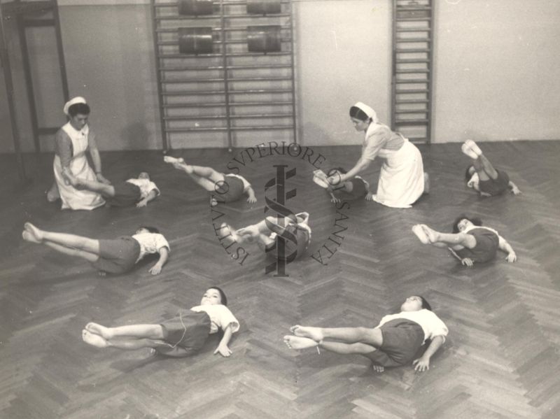 Sala per la ginnastica collettiva dell'Istituto Ortopedico "Luigi Spolverini" di Ariccia (Roma) - delle infermiere controllano la postura di un gruppo di bambini che svolgono esercizi ginnici