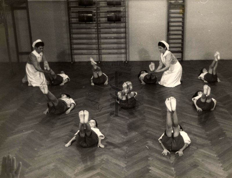 Sala per la ginnastica collettiva dell'Istituto Ortopedico "Luigi Spolverini" di Ariccia (Roma) - delle infermiere controllano la postura di un gruppo di bambini che svolgono esercizi ginnici