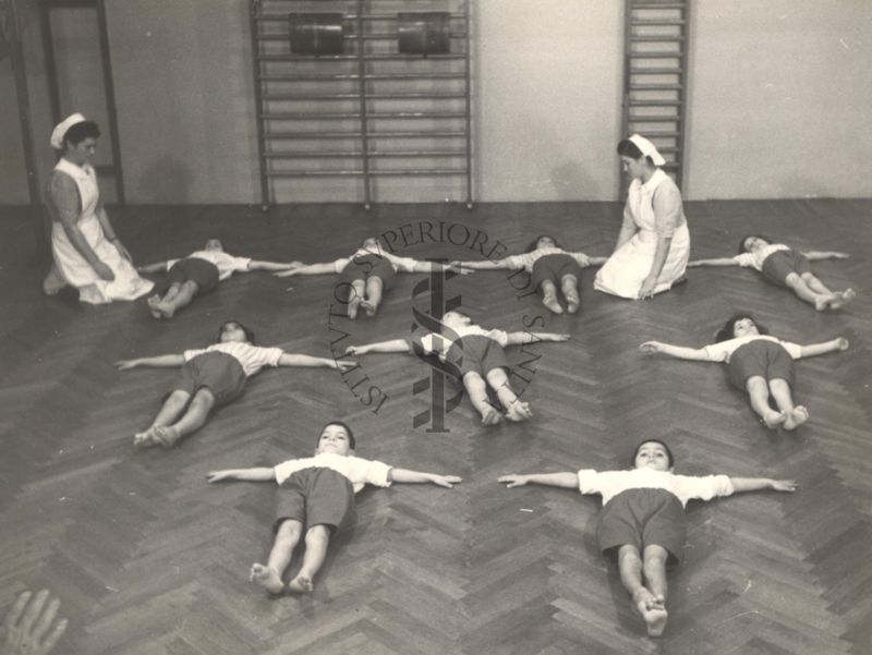 Sala per la ginnastica collettiva dell'Istituto Ortopedico "Luigi Spolverini" di Ariccia (Roma) - delle infermiere controllano la postura di un gruppo di bambini che svolgono esercizi ginnici