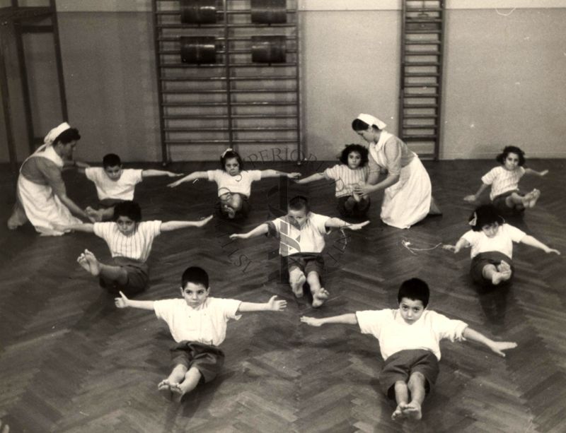 Sala per la ginnastica collettiva dell'Istituto Ortopedico "Luigi Spolverini" di Ariccia (Roma) - delle infermiere controllano la postura di un gruppo di bambini che svolgono esercizi ginnici