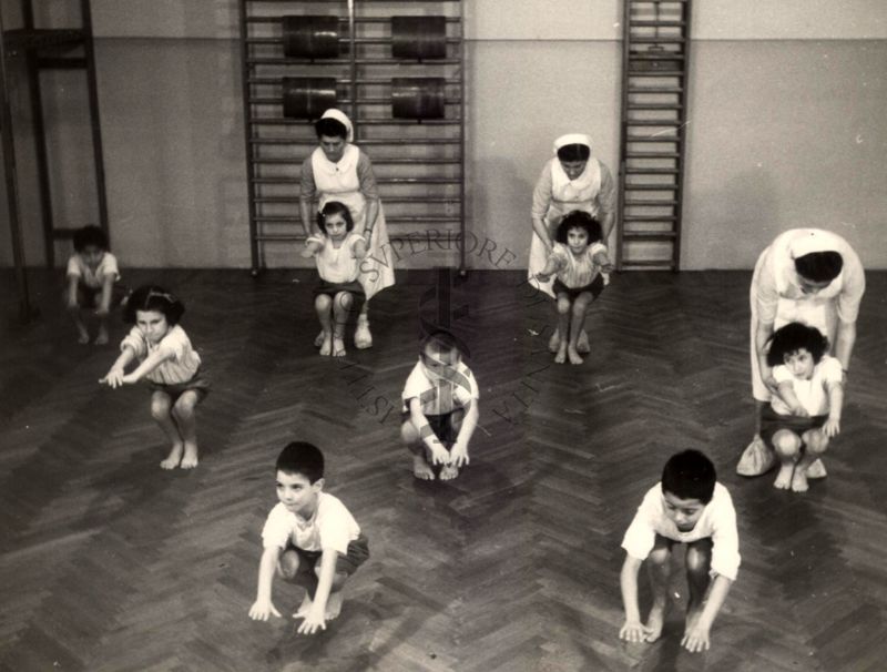 Sala per la ginnastica collettiva dell'Istituto Ortopedico "Luigi Spolverini" di Ariccia (Roma) - delle infermiere controllano la postura di un gruppo di bambini che svolgono esercizi ginnici