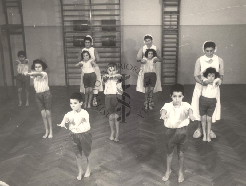 Sala per la ginnastica collettiva dell'Istituto Ortopedico "Luigi Spolverini" di Ariccia (Roma) - delle infermiere controllano la postura di un gruppo di bambini che svolgono esercizi ginnici