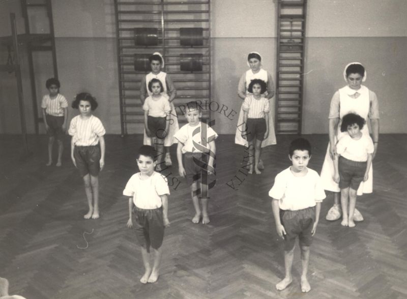 Sala per la ginnastica collettiva dell'Istituto Ortopedico "Luigi Spolverini" di Ariccia (Roma) - delle infermiere controllano la postura di un gruppo di bambini che svolgono esercizi ginnici