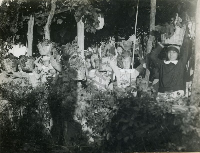 Bambini con ceste d'uva alla festa della vendemmia nella Colonia Antimalarica "Bartolomeo Gosio"