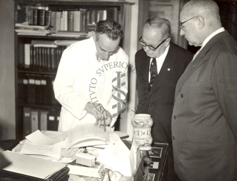 Il Prof. Daniel Bovet mostra dei grafici stampati al Prof. Bernard Houssay, accompagnati dal Prof. Domenico Marotta (a destra)