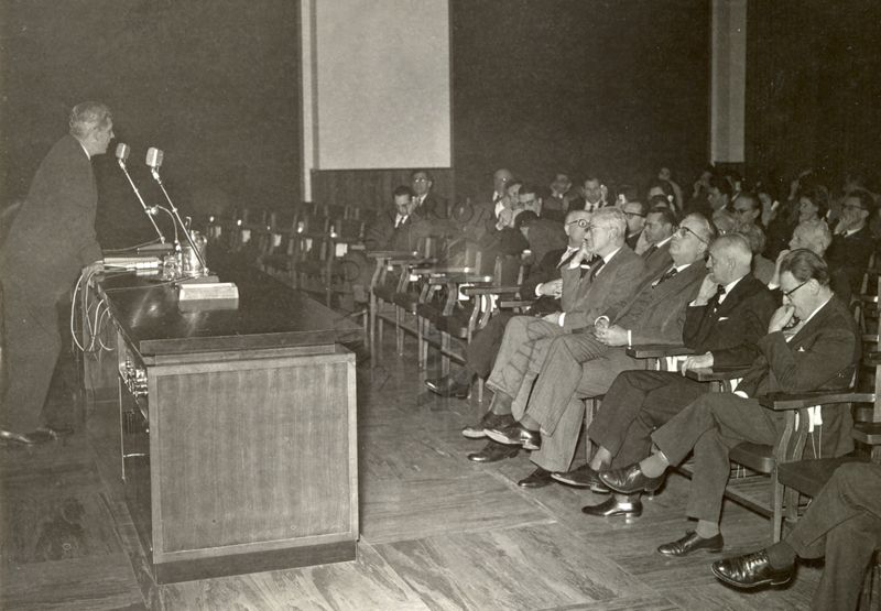 Conferenza del Dr. Joseph Edward Rall, endocrinologo statunitense,  nell'aula magna dell'Istituto Superiore di Sanità; riconoscibili, tra il pubblico, in prima fila: il Prof. Giordano Giacomello, il Prof. Giovanni Battista Marini Bettolo