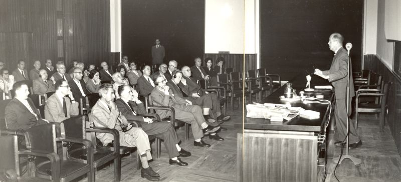 Immagine del relatore in piedi dietro la cattedra mentre tiene la conferenza di fronte all'uditorio, in cui sono presenti: il Dott. Massimo Pantaleoni (ultima fila), il Dott. Giovanni Battista Marini Bettolo (penultima fila), il Prof. Domenico Marotta (prima fila)