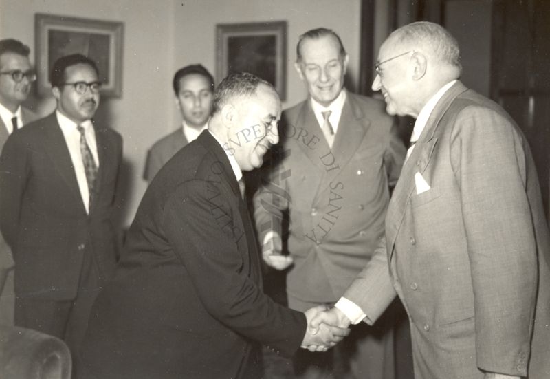 Il Prof. Domenico Marotta (a destra) stringe la mano al Ministro della Sanità della Cirenaica (a sinistra). Dietro di loro il Dott. Massimo Pantaleoni