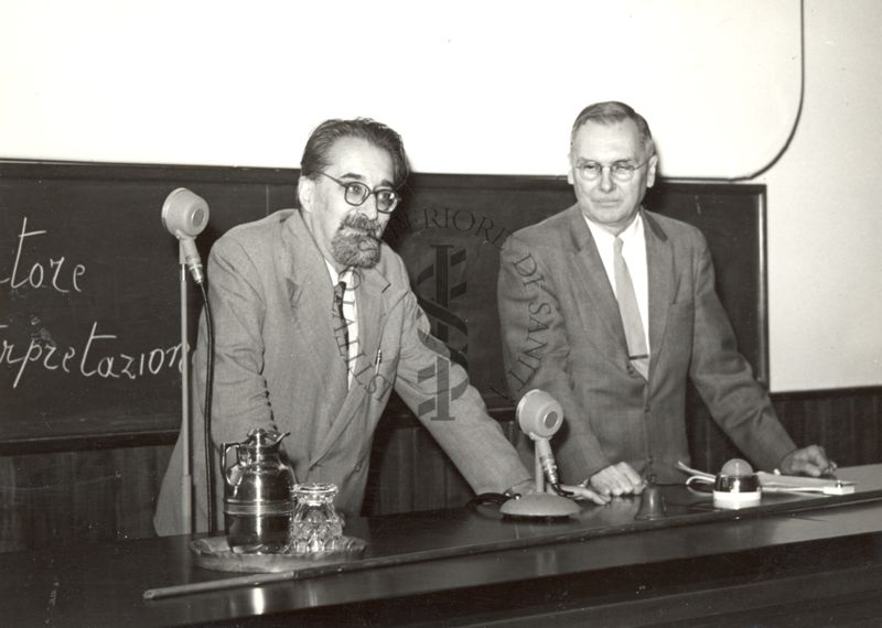 Intervento in aula del Prof. Francesco Giordani (a sinistra) accanto al Prof. Hugh Dryden (a destra) dietro alla cattedra dei relatori, in occasione della conferenza tenuta all'Istituto Superiore della Sanità