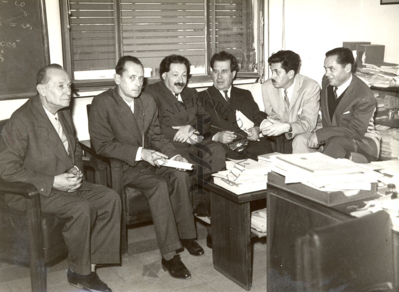 Il gruppo degli studiosi russi in visita all'Istituto Superiore di Sanità seduto in un ufficio insieme al Prof. Ernst Boris Chain (terzo da sinistra) e il Dott. Massimo Pantaleoni (primo a sinistra)