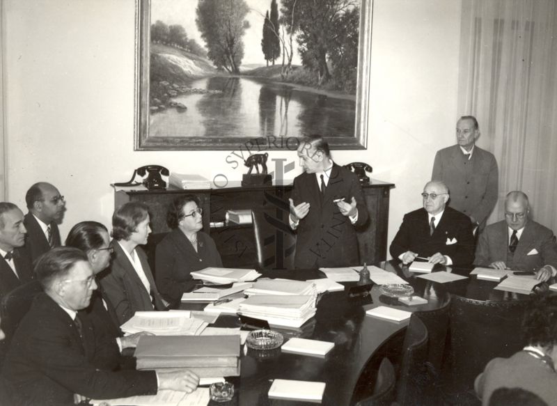 Foto di parte del gruppo di funzionari dell'Unione Europea Occidentale presenti in riunione in Istituto Superiore di Sanità, intervento del Ministro Camillo Giardina (al centro in piedi); di seguito, seduto a destra il Prof. Domenico Marotta ed (in piedi, sulla destra) il Prof. Massimo Pantaleoni