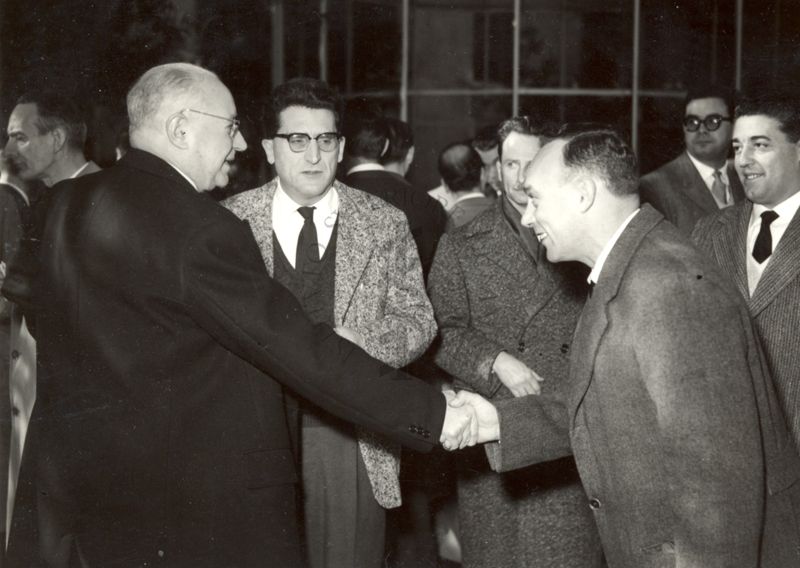 Il Prof. Domenico Marotta (a sinistra) stringe la mano ad un dipendente dell'Istituto Superiore di Sanità, circondato da altri colleghi, in ambiente chiuso