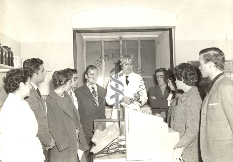 Il Dott. Marini Bettolo (al centro) mostra un laboratorio dell'Istituto Superiore di Sanità a un gruppo di studenti cileni in visita, presente anche una dipendente dell'Istituto (in camice, a sinistra)
